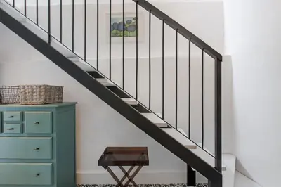 a staircase with black railings and a green dresser at The Village Loft in Caniço