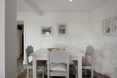 a white dining room with a white table and chairs at The Village Loft in Caniço