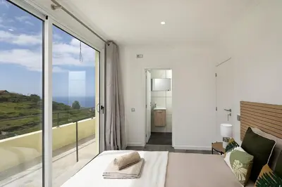 a bedroom with a bed and a large window at Franco's House II, Mar e Serra in Estreito da Calheta