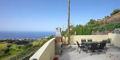a patio with chairs and a table on a wall at Franco's House II, Mar e Serra in Estreito da Calheta