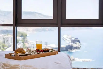 a tray of food on a bed with a drink at Infinity View by Homie in Funchal