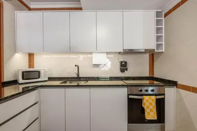a kitchen with white cabinets and a sink and a microwave at Pestanas Nest by Homie in Ribeira Brava