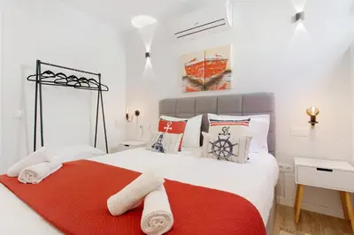 a white bedroom with a red and white bed at O Marinheiro 15B in Machico