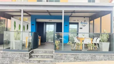 a kitchen with a table with white chairs and a microwave at O Marinheiro 15B in Machico