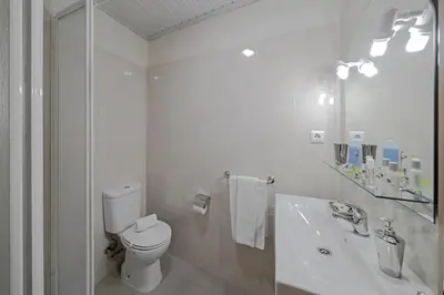 a white bathroom with a toilet and a sink at OurMadeira - Taberna Apartments in Funchal