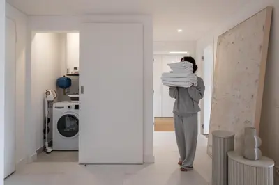 a woman standing in a hallway holding a stack of towels at Acqua Residence VI by An Island Apart in Funchal