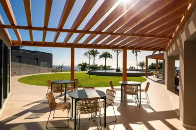 a patio with tables and chairs under a wooden pergola at Acqua Residence VI by An Island Apart in Funchal