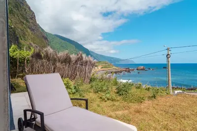 a white chair sitting on a porch overlooking the ocean at GuestReady - Relax & Ride the Waves in São Vicente
