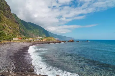 a beach with a rocky shoreline with mountains in the background at GuestReady - Relax & Ride the Waves in São Vicente