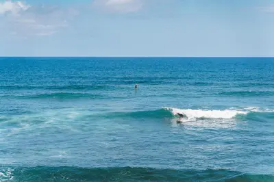 a person riding a wave on a surfboard in the ocean at GuestReady - Relax & Ride the Waves in São Vicente