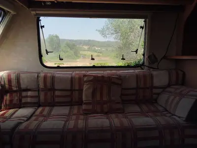 a couch in the back of a bus with a window at Uljanas caravana for 2 with view of the rescued horses in Barão de São João