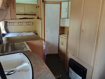 a small room with a sink and a bed at Uljanas caravana for 2 with view of the rescued horses in Barão de São João
