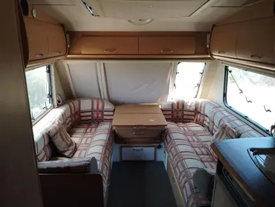 an interior of an rv with a table and couch at Uljanas caravana for 2 with view of the rescued horses in Barão de São João