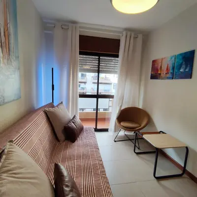 a bedroom with a bed with a chair and a window at Sol II in Funchal