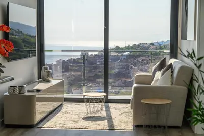 a living room with a couch and a large window at Ocean Valley by Mth in Ribeira Brava