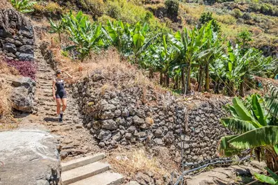 a woman walking down a rocky trail at Atlantic Pebble Villa in Ribeira Brava