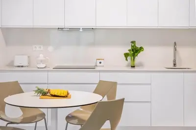 a white kitchen with a white table and chairs at Atlantic Pebble Villa in Ribeira Brava