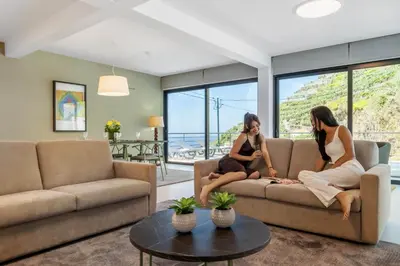 two women sitting on a couch in a living room at Atlantic Pebble Villa in Ribeira Brava