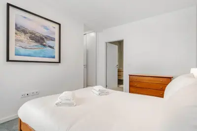 a white bedroom with a bed and a picture on the wall at Atlantic Pebble Villa in Ribeira Brava