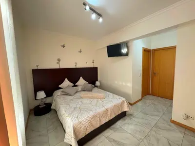a bedroom with a bed and a flat screen tv at Funchal Cozy Private Room, Ensuite Bathroom, WiFi and Great Location in Funchal