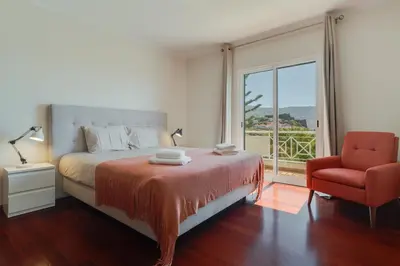 a bedroom with a bed and a chair and a window at Sao Joao- 3 Bedroom apartment in Funchal