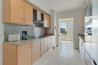 a kitchen with wooden cabinets and a white tile floor at Sao Joao- 3 Bedroom apartment in Funchal