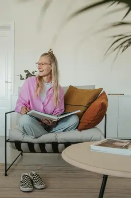 a woman sitting on a couch reading a book at Outsite Sagres - Work, Connect, Explore in Sagres