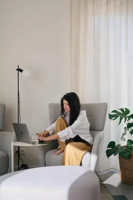 a woman sitting on a couch with a laptop at Outsite Sagres - Work, Connect, Explore in Sagres