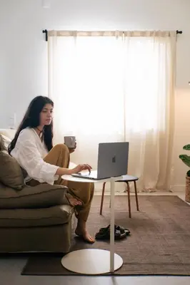 a woman sitting on a couch with a laptop on a table at Outsite Sagres - Work, Connect, Explore in Sagres