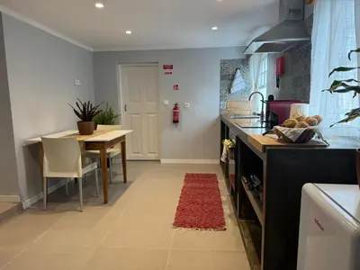 a kitchen with a table and a red rug on the floor at Refúgio do Nevoeiro Apart T1 in Porto Moniz