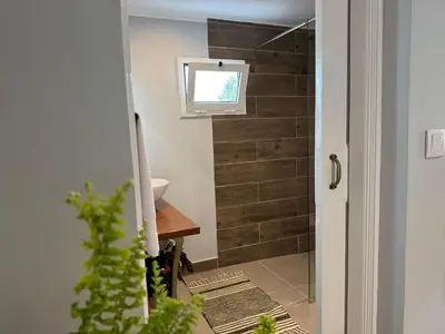 a bathroom with a wooden wall with a window at Refúgio do Nevoeiro Apart T1 in Porto Moniz