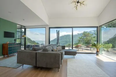 a living room with a couch and a large window at Panorama House by LovelyStay in São Vicente