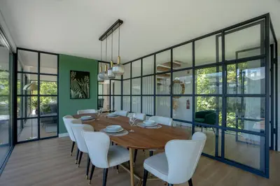a dining room with a wooden table and white chairs at Panorama House by LovelyStay in São Vicente