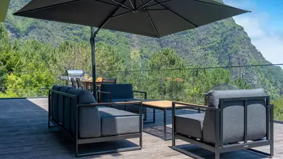 a patio with a table and chairs and an umbrella at Panorama House by LovelyStay in São Vicente