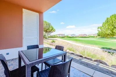 a patio with a table and chairs and a golf course at Casa Maria at Boavista Resort Lagos in Atalaia