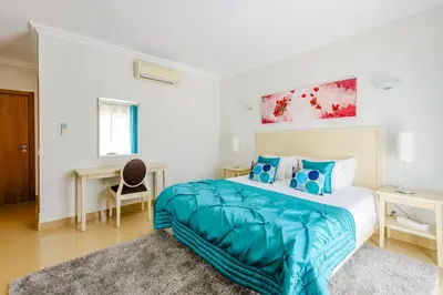 a bedroom with a bed with a blue comforter at Casa Maria at Boavista Resort Lagos in Atalaia