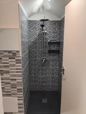 a bathroom with a shower with a black and gray tiles at MM House in Bicas