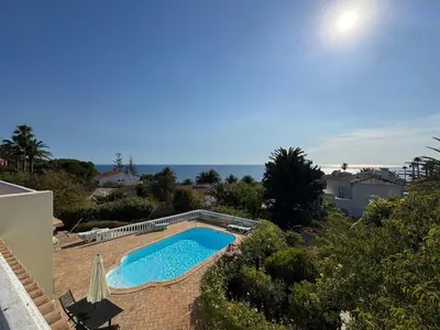 a swimming pool in a yard with the ocean in the background at Casa Tenente Camilo in Lagos