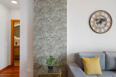 a living room with a couch and a clock on a wall at Ti Clara View Apartment in Caniço