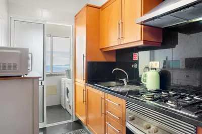 a kitchen with wooden cabinets and a stove top oven at Ti Clara View Apartment in Caniço