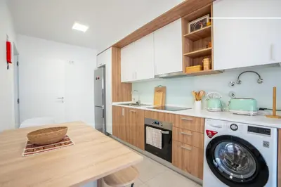 a kitchen with a washing machine and a wooden counter at Hygge Madeira by LovelyStay in Caniço