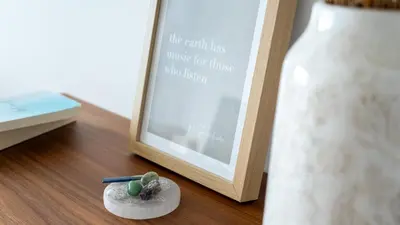 a candle on a plate next to a picture and a bottle at Hygge Madeira by LovelyStay in Caniço