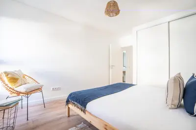 a white bedroom with a bed and a chair at Hygge Madeira by LovelyStay in Caniço