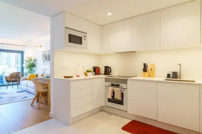 a kitchen with white cabinets and a living room at GuestReady - Soothing escape in Funchal in Funchal