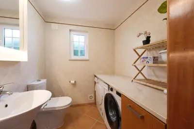 a bathroom with a washing machine and a sink at Villa Oxalis by Destination Algarve in Atalaia