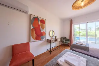 a bedroom with a bed and a chair and a window at Villa Oxalis by Destination Algarve in Atalaia