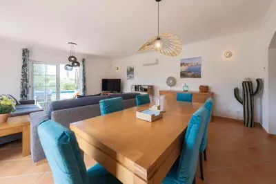 a dining room and living room with a wooden table and blue chairs at Villa Oxalis by Destination Algarve in Atalaia
