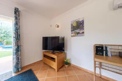 a living room with a flat screen tv on a wooden stand at Villa Oxalis by Destination Algarve in Atalaia