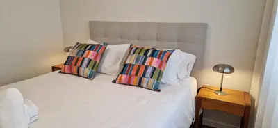 a bedroom with a white bed with two colorful pillows at Shell Living - KOS in Funchal