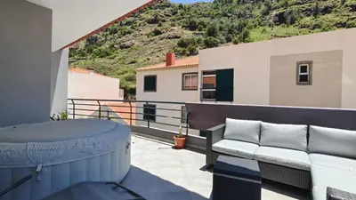 a balcony with a bench and a table and a mountain at Apartamento Luar in Ribeira Brava